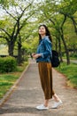 Full length of cheerful traveler standing in the path looking up to the sky. elegant woman enjoy the beauty ofÃÂ the green park in